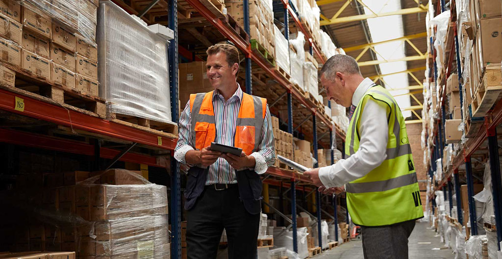 Employé scannant des étiquettes sur des étagères dans un entrepôt propre avec un système de rangement clairement identifié
